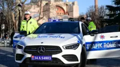 Lüks bir trafik polisi aracının başında bir polis poz veriyor.