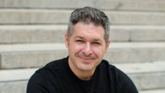 Psicólogo sorrindo contidamente, sentado em escadaria