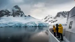 Três pessoas em barco observando geleiras; uma delas tira foto