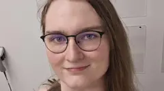 Hannah Kreager é uma mulher branca que usa óculos de grau e tem cabelos castanhos claros