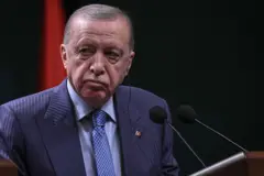 أردوغان وحده يظهر في الصورة يرتدي بدلة رسمية يميل لونها إلى الكحلي ومقلمة، والقميص أزرق فاتح، وربطة العنق زرقاء مزخرفة بدرجات مختلفة من ذات اللون.
