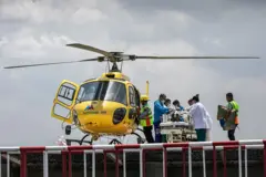 O helicóptero que levou o guia ao hospital. Italianos e médicos cercam a maca onde o sobrevivente está deitado