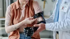 un doctor le coloca una protésis a una mujer con el brazo amputado. no se ven los rostros 