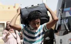 صورة لشاب سوداني يحمل حقيبة سفره خلال عبوره من السودان إلى مصر
