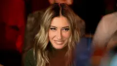 Şeyma Subaşı beyaz dişleri gözükecek şekilde gülüyor, saçlar sarı yanlarda.