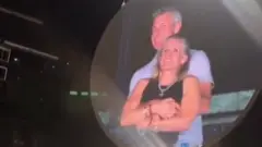 Un couple enlacé est projeté sur un écran géant pendant un concert de Coldplay.