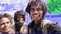 Three members of the Sudanese Rapid Support Forces smile at the camera in front of destroyed cars near El Fasher.