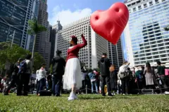 2024年2月14日情人節，香港一名女子手持著巨型的紅心裝置「Chubby Hearts」。