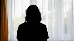 Una mujer mira hacia afuera por la ventana.
