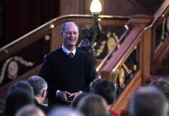 Robert Ballard, un hombre de mediana edad con calvicie prematura, se dirige a un grupo de personas frente a una exposición del Titanic