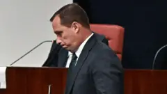 Cid caminhando em sala de audiência, olhando para baixo