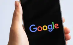 Mano sostiene un celular en cuya pantalla se lee Google.