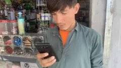 ስልኩ እየተጠቀመ ያለ አፍጋኒስታናዊ