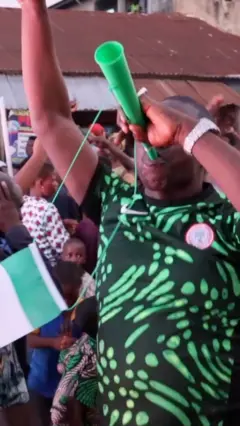 Onye egwu bọọlụ na-amasị nye uwe nke otu egwu bọọlụ Naịjirịa, jide opi na-acha akwụkwọ ndụ ma welie aka elu.