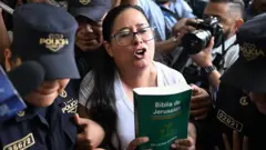 A advogada e ativista dos direitos humanos salvadorenha Ruth López, escoltada pela polícia para uma audiência no centro judicial Isidro Menéndez, em San Salvador, com uma bíblia nas mãos