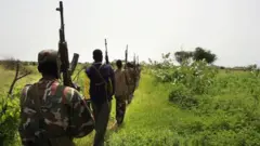 Wasu mutane riƙe da makamai sun yi layi suna tafiya sun juya baya