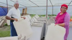 म्याग्दीस्थित नेपाली हातेकागज उद्योगमा उत्पादित कागज देखाउँदै सञ्चालकहरू 