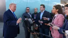 Trump, Air Force One uçağı yanında mikrofonlar önünde basına konuşuyor.