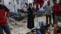 Una mujer mira con tristeza a los heridos de un ataque ocurrido dentro de un lugar de distribución de comida.