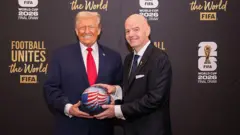 Дональд Трамп и Джанни Инфантино держат в руках мяч чемпионата с нарисованным на нем американским флагом