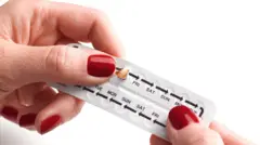 Mulher segura cartela de anticoncepcionais para uso oral