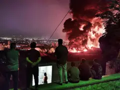 Personas observando el fuego y el humo tras un ataque israelí contra el depósito de petróleo de Shahran, el 15 de junio de 2025, en Teherán.