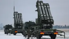 Системы Patriot, рядом стоит военный, на земле лежит снег.