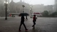 Pessoas caminham durante tempestade no centro de São Paulo
