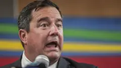 South Africa's Democratic Alliance (DA) leader John Steenhuisen wit im mouth open and micorphone for im front