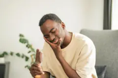 Homme avec une glace dans la main et qui se tient le menton avec l'autre.