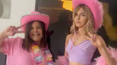 Michelle e Isla Sneddon fazem sinais de 'paz' e posam para a câmera. As duas usam chapéus de caubói rosa e estão vestidas de rosa e roxo. Michelle tem cabelo castanho e usa um colar de flores. Isla tem cabelo loiro e usa uma echarpe de penas.