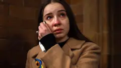 ইউক্রেন যুদ্ধের এক বছরে ক্যাথেড্রালে কাঁদছেন এক নারী