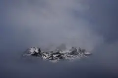 La cresta nevada de las montañas en el paso de Stelvio, entre nubes