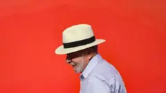 Presidente Lula usando chapéu em um fundo laranja