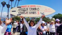 Una mujer sostiene una tabla de surf con la inscripción "Muertes de surfistas-Ataques de tiburones: 0 y Ataques humanos: 3" durante una protesta.