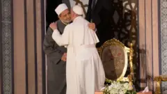 پاپ فرانسیس د ۲۰۱۷ د اپریل پر ۲۸مه، په قاهره کې د الازهر له لوی امام احمد الطیب سره په غېږه روغبړ کوي
