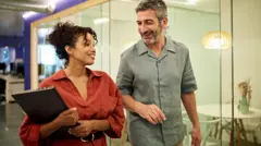 Uma mulher e um homem entram num escritório conversando