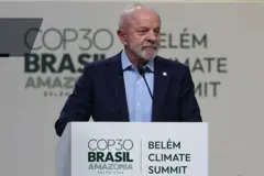 Presidente Lula falando no palco da COP30, em Belém. Ele usa um terno azul marinho. No púlpito está escrito COP30 Brasil Amazônia.
