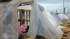 Bebê deslocado dorme dentro de uma tenda em um estacionamento junto ao mar em Beirute, no Líbano, no dia 22 de março de 2026