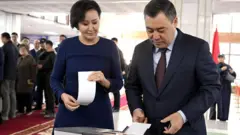 Президент Кыргызстана Садыр Жапаров (справа) и его супруга Айгуль Жапарова (слева) голосуют на избирательном участке № 1046 в Бишкекском государственном университете в Бишкеке, Кыргызстан, 30 ноября 2025 года