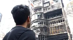 বেইলি রোডে আগুনে পুড়ে যাওয়া ভবনটি দেখছেন সে রাতে আগুন থেকে বেঁচে ফেরাএকজন 