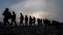 صفی از پناهجویان در تاریکی شب حرکت می‌کنند