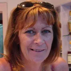 Mulher com cabelo até os ombros e óculos de sol sobre a cabeça, sorrindo para a câmera