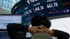 Um corretor de câmbio analisa uma tela que mostra o Índice de Preços de Ações Composto da Coreia (KOSPI) e a taxa de câmbio entre os EUA