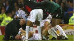 آندری شوچنکو (دراز کشیده روی زمین) یک گل مردود در وقتی عادی بازی داشت، اما سپس با گل کردن یک پنالتی‌ سرنوشت‌ساز، به آث میلان کمک کرد، قهرمان لیگ قهرمانان ۲۰۰۳ در اولدترافورد شود