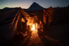 صابرين، فلسطينية نازحة، 42 عاماً، وهي أم لسبعة أطفال، تطبخ على نار مفتوحة جنوب قطاع غزة، 30 نوفمبر/تشرين الثاني 2025، حيث تواجه ظروفاً إنسانية قاسية في مخيم غير رسمي في خان يونس، تفاقمت بسبب الفقر المدقع والطقس القاسي. 