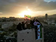 صورة أرشيفية: تظهر صورة التقطتها طائرة بدون طيار أشخاصًا يلوحون بالأعلام التي تبناها الحكام السوريون الجدد خلال الاحتفالات في ساحة الأمويين في دمشق.