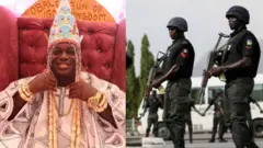 Awọn ọlọpaa meji duro wamawamu pẹlu ibọn lọwọ wọ, wọn wọ koto lori aṣọ dudu pẹlu ṣokoto kaaki