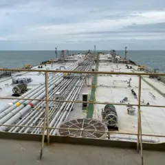 Imagem do navio Gale tirada de uma plataforma, em direção à frente do petroleiro. Há grades em primeiro plano e o céu é visível ao fundo