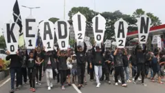 Suporter Arema FC (Aremania) melakukan longmarch dan memblokir jalan saat berunjuk rasa di perempatan jalan Ciliwung, Malang, Jawa Timur, Minggu (4/12/2022). 